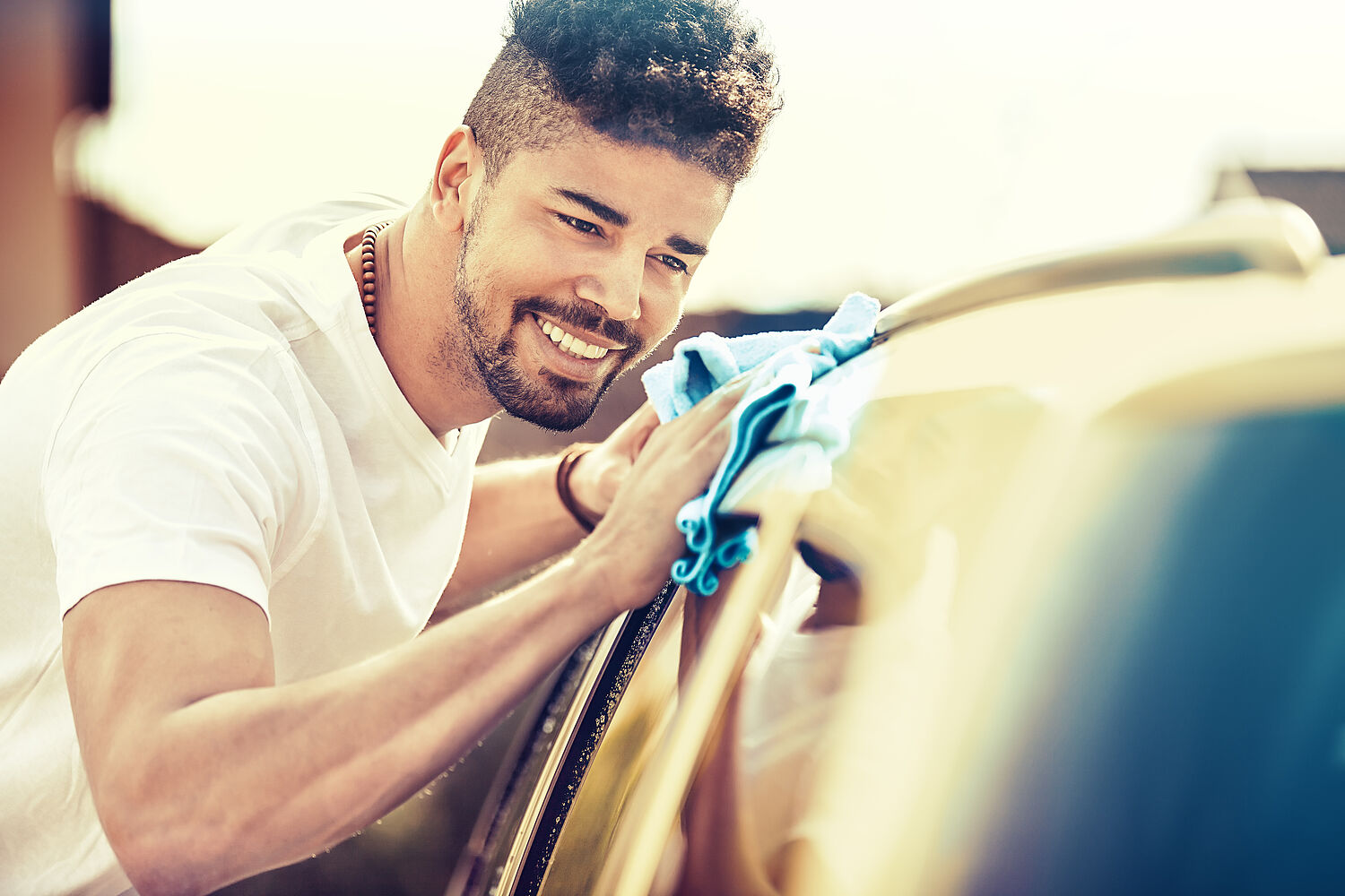 Young handsome man is washing car outdoor.